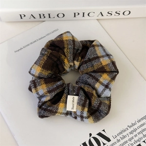 Detail of handmade plaid scrunchie with woven texture and a visible Hand Made label