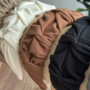 Detailed close-up of pleated fabric headbands in various colors on a rustic display stand