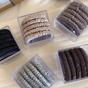 Close-up of 5-piece satin scrunchies set in elegant neutral tones and acrylic packaging