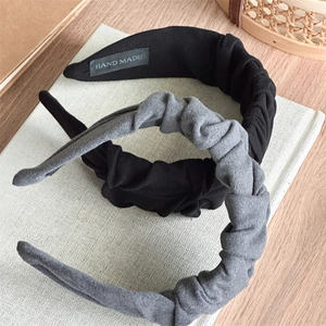 Close-up of pleated fabric headbands in black and grey with handmade label detail