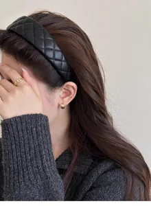 Detail of black quilted faux leather headband with gold ring and earring accessories