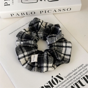 Detailed macro view of black and white plaid scrunchie with woven Hand Made label tag