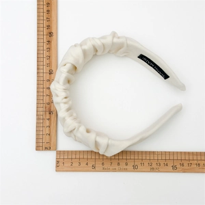 Detailed top view of white pleated fabric headband with measurement scales for dimensions