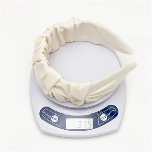 Minimalist cream pleated fabric wide headband weighing 37.9 grams on a white scale