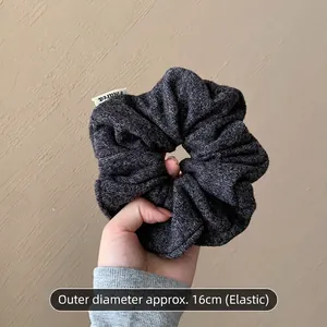 Détail macro d'un grand chouchou en maille grise avec un diamètre de 16 cm et élastique