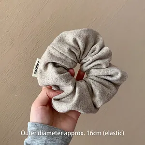 Gros plan d'un chouchou géant en maille douce gris avoine avec diamètre élastique de 16cm