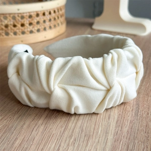 Detailed view of cream fabric headband with pleated texture on a natural wooden background