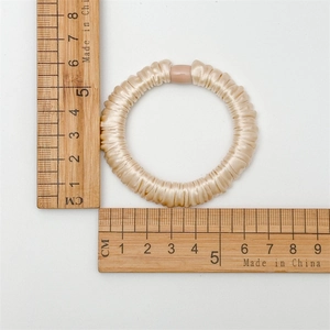 Detail of champagne satin scrunchie with 5.5cm outer diameter shown on ruler
