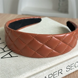 Close-up of caramel brown quilted faux leather headband with classic diamond stitch pattern