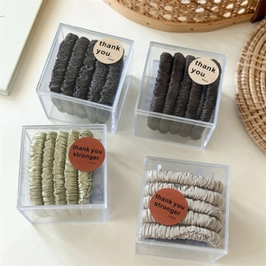 Set of 5 satin scrunchies in earth tones displayed in transparent acrylic gift boxes