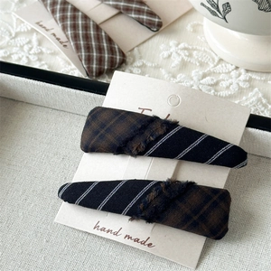Detail of plaid fabric hair clips with fringe edges on a handmade display card