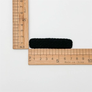 Detailed view of a black twill fabric hair clip showing 5cm length on a ruler scale