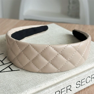 Detail of beige quilted faux leather headband with diamond stitch on a book
