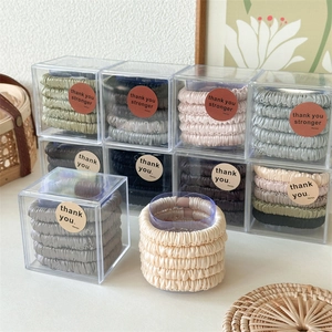 Detail of multi-color satin scrunchies set in clear gift packaging with smooth texture