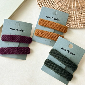 Set of twill fabric hair clips in purple, yellow and green on a paper display card