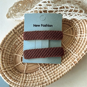 Detail of dark brown twill fabric hair clips in a pair set on a decorative display card