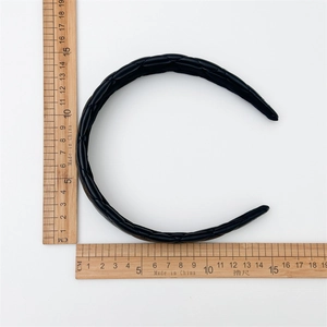 Macro shot showing dimensions of black quilted leather headband on white background
