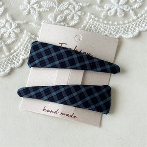 Close-up of blue and black plaid fabric hair clips on a white display card
