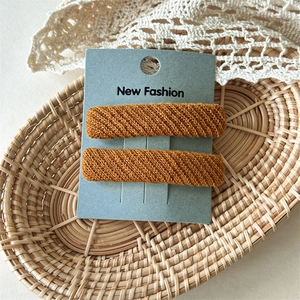 Detail of two brown twill knit hair clips on a New Fashion display card in a basket
