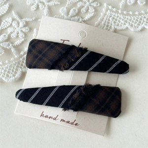 Detail of plaid fabric hair clips with fringe edges and handmade texture on lace
