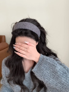 Dettaglio del cerchietto in maglia grigia su capelli lunghi con texture morbida