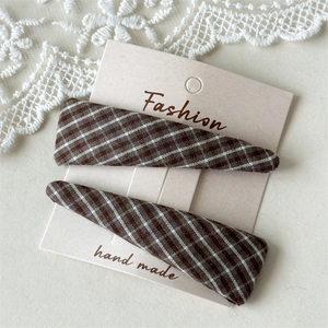Detail of plaid fabric triangle hair clips on display card with white lace accents