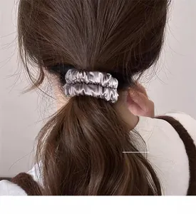 Détail d'un chouchou en satin gris argenté montrant la texture plissée sur un mannequin