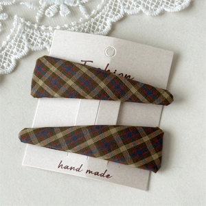Detail of two handmade plaid fabric BB hair clips on a vintage decorative card