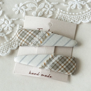 Detail of plaid fabric hair clips with fringe edges and rustic beige card display