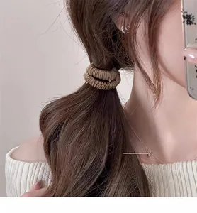 Détail d'un chouchou plissé en satin marron café sur une coiffure en queue de cheval basse