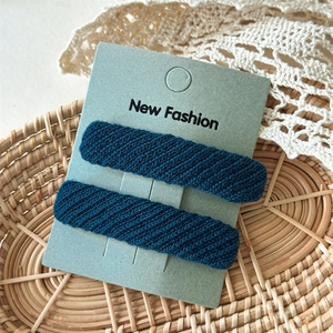 Detail of dark blue twill fabric hair clips in a rustic woven basket with lace