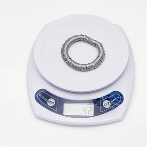Vue détaillée macro montrant le poids de 4,2g du chouchou en satin gris argenté plissé