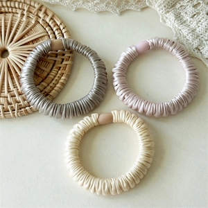 Détail de chouchous en satin plissé argent, rose et beige avec des boucles mates