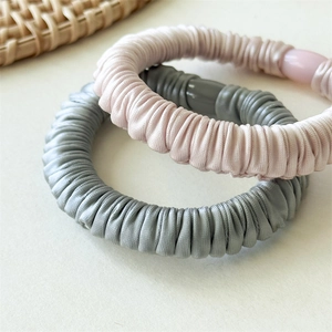 Gros plan de chouchous plissés en satin gris et rose avec des détails décoratifs