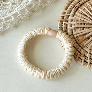Détail d'un chouchou en satin crème avec texture plissée et boucle translucide chic