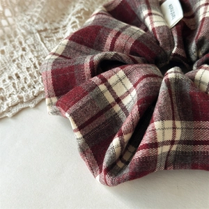 Detail of red and grey plaid scrunchie with a handmade woven label and cotton texture