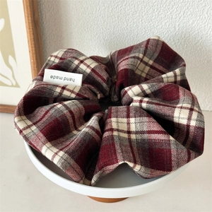 Detail of red and white plaid scrunchie with handmade label on white ceramic plate