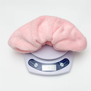 Pink plush coral fleece scrunchie weighing 43.8g shown on a digital scale for accuracy