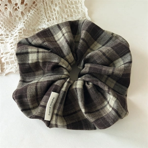 Detailed view of dark vintage plaid scrunchie featuring a handmade woven label detail