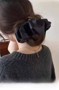 Close-up of black satin scrunchie with floral rose embroidery on a female hairstyle