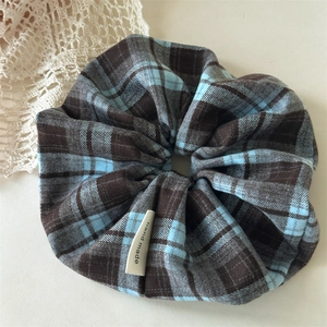 Detail of blue and brown plaid fabric scrunchie with handmade woven label