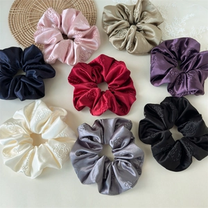 Detailed macro view of embossed rose texture on luxury silk satin hair scrunchies set