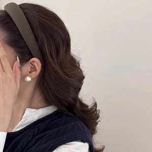 Close-up of a wide brown fabric padded headband with elegant champagne pearl earrings