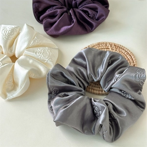 Satin floral scrunchies in purple, white, and blue with embossed camellia textures
