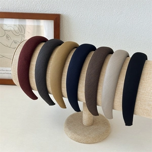 Set of seven solid color thick sponge headbands on a rustic display stand