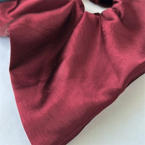 Detail showing the glossy texture and wine red satin fabric of this elegant hair scrunchie