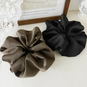 Close-up of premium satin scrunchies in brown and black with elegant silk texture