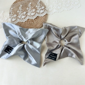 Detail of satin scrunchies in silver blue and champagne with handmade label