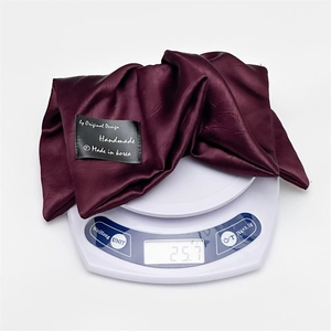 Detail shot of a dark red satin hair scrunchie weighing 25.7g on a digital scale