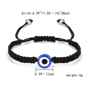 Close-up of adjustable evil eye charm bracelet with blue bead on black woven rope